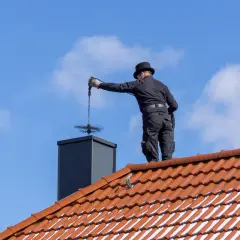 Kominiarz na dachu czyści komin, ale nie czyści dachówek.