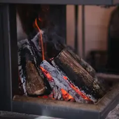Płonące drewno w kominku, żar rozświetla popiół. To idealne rozwiązanie dla tych, którzy szukają wydajnych kotłów co 5 klasy.