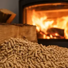 Piec z płonącym ogniem i sterta pelletu obok drewna. Czy kominek na pellet się opłaca?