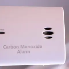 Biały czujnik czadu z przyciskiem Test/Reset i napisami "Alarm", "Move to Fresh Air", "Operate", "Carbon Monoxide Alarm".