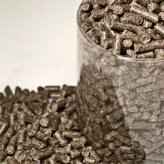 Zbliżenie na pellet drzewny w przezroczystym pojemniku i rozsypany obok. Rozważasz, jak importować pellet z Ukrainy?