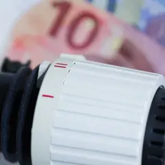 Termostat grzejnika obok banknotów 10 euro. Czy to grzejnik olejowy czy na podczerwień, ogrzewanie kosztuje.