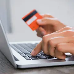 Ręce wpisują dane karty na laptopie, szukając, gdzie kupić ekogroszek przez internet.
