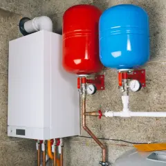 Nowoczesny biały kocioł z dwoma zasobnikami (czerwonym i niebieskim) i manometrami. Czy kocioł elektryczny można odliczyć od podatku?