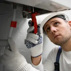 Fachowiec w białej rękawicy dokręca śrubę przy kotle CO w Kutnie.