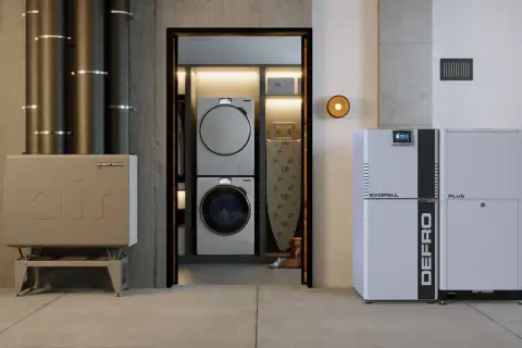 Nowoczesny kocioł co z podajnikiem 15 kW marki DEFRO, obok pralki i suszarki w pralni.