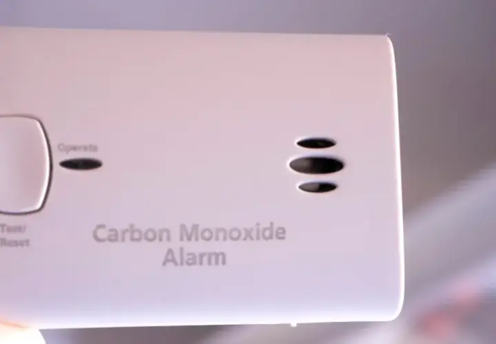 Biały czujnik czadu z przyciskiem Test/Reset i napisami "Alarm", "Move to Fresh Air", "Operate", "Carbon Monoxide Alarm".