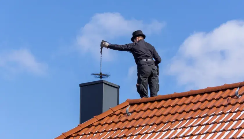 Kominiarz na dachu czyści komin, ale nie czyści dachówek.