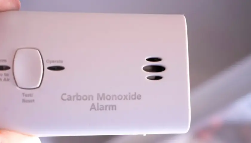 Biały czujnik czadu z przyciskiem Test/Reset i napisami "Alarm", "Move to Fresh Air", "Operate", "Carbon Monoxide Alarm".