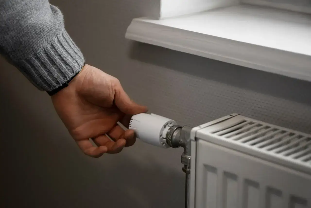 Dłoń reguluje termostat grzejnika. Zastanawiasz się, dlaczego grzejnik nie grzeje mimo odpowietrzenia? Może problem leży gdzie indziej.